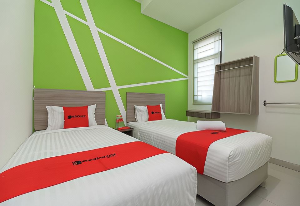 a hotel room with two beds , one on the left and one on the right side of the room at RedDoorz Plus Near Uin Raden Fatah Palembang