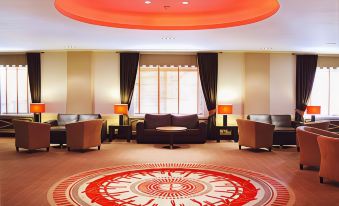 a modern living room with a red and orange circular rug , black couches , and various decorative elements at The Dragon Hotel