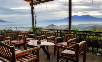 a dining area with wooden chairs and tables , surrounded by a view of the mountains at Cikidang Plantation Resort