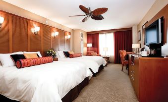 a hotel room with two beds , white bedding , and red pillows , along with a ceiling fan and a window at Isle Casino Hotel Waterloo