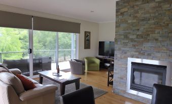 a spacious living room with a fireplace , comfortable seating , and a flat - screen tv mounted on the wall at Abby's Cottages