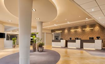 a hotel lobby with a check - in desk , a reception desk , and several chairs arranged around it at DoubleTree by Hilton Manchester Airport