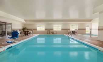a large , empty swimming pool with blue water and white tiles , surrounded by chairs and tables in an indoor area at Country Inn & Suites by Radisson, Ashland - Hanover, VA