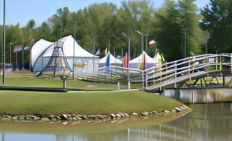 a park with tents , swings , and other play equipment , surrounded by a grassy area and a body of water at Indiana Beach Accommodations