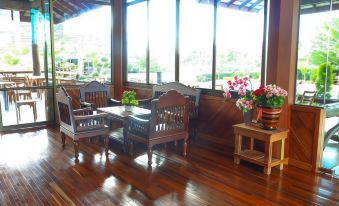 a wooden patio with a dining table and chairs , surrounded by potted plants and flowers at Palmsuay Resort
