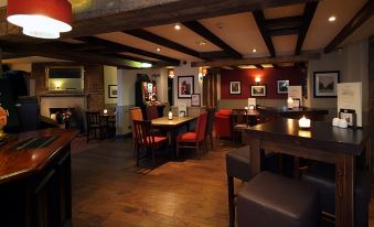 a restaurant with wooden tables and chairs , red walls , and framed pictures on the walls at Swindon North