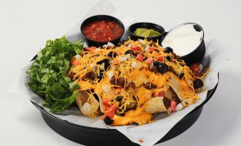 a black tray filled with a variety of nachos , accompanied by various condiments and side dishes at AmericInn by Wyndham Valley City Conference Center