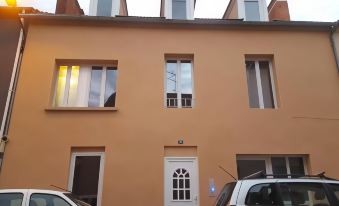 a beige house with white trim , two cars parked in front , and a window with a view of the sky at Vichy