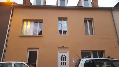 a beige building with white trim and large windows , with cars parked in front of it at Vichy