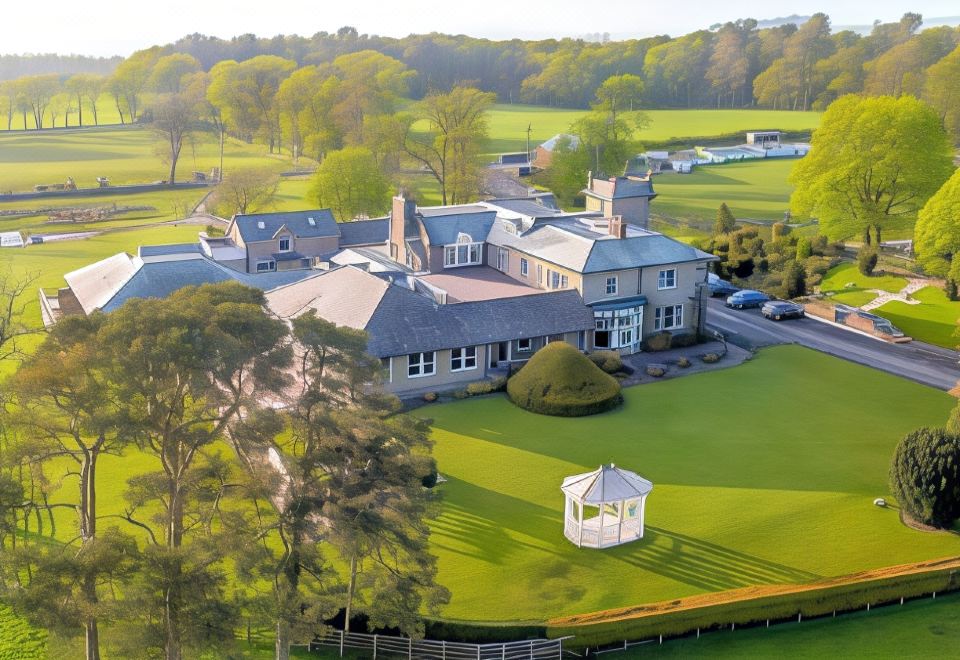 aerial view of a large stone house surrounded by grass , trees , and a gazebo in the background at Hundith Hill Hotel