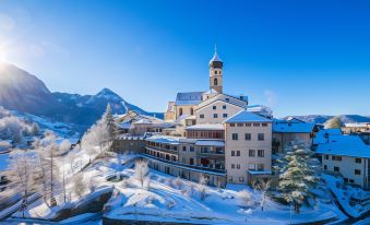 a snow - covered mountain village with a large building in the center , surrounded by snow - covered fields and trees at Romantik Hotel Turm