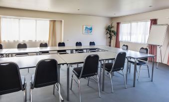 a conference room with a long table surrounded by chairs and large windows , providing natural light at Auckland Airport Motel