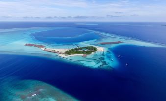 aerial view of a small island surrounded by the ocean , with a sandy beach in the center at Constance Moofushi