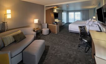 a modern hotel room with a comfortable bed , couch , chairs , and desk , along with some other furniture at Courtyard Bay City