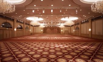 a large , empty ballroom with a red carpet and multiple chandeliers hanging from the ceiling at Imabari Kokusai Hotel