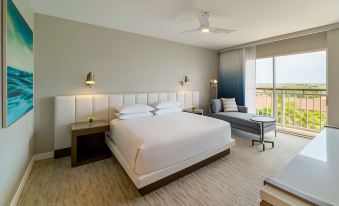 a large , modern hotel room with a white bed , two nightstands , and a window overlooking the ocean at Hyatt Regency Aruba Resort, Spa and Casino