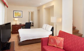 a modern hotel room with a large bed , white bedding , and a red couch , along with a desk and chair at Residence Inn Denver Tech Center
