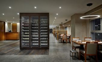 a modern restaurant with a wine cellar , showcasing a variety of wines in large bottles at LOTTE CITY HOTEL ULSAN