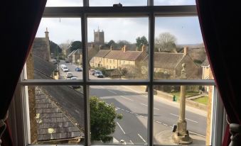 a view from a window of a church window , looking out over a street and a small town at The White Hart Hotel