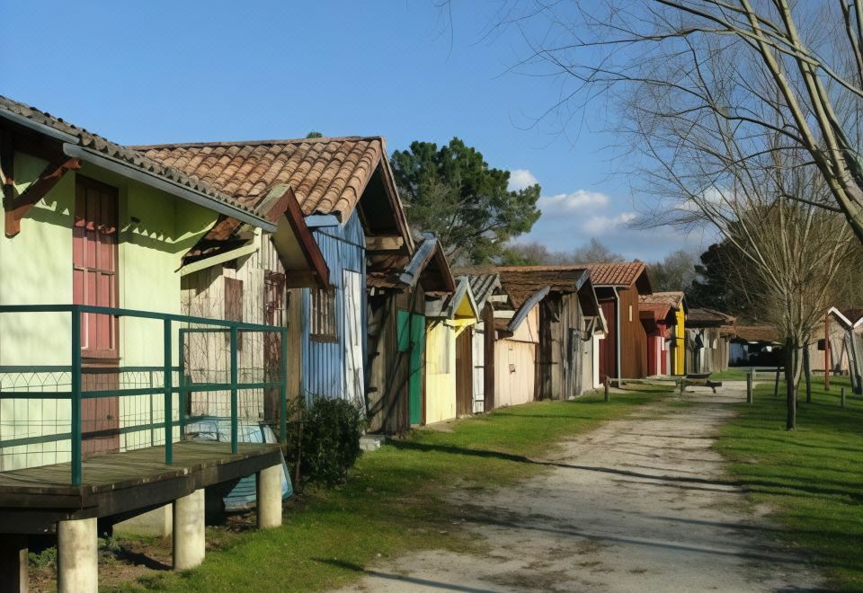 a row of colorful houses with tiled roofs and wooden fences , situated in a grassy area at Les Flots Bleus