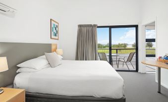 a modern bedroom with white bedding , large windows offering views of the outdoors , and a balcony overlooking the valley at Corrigans Cove
