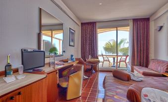 a hotel room with a living area , dining table , and a view of the ocean at Hotel Antares