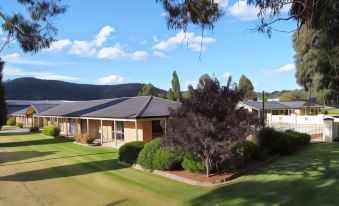 a house with a large yard and trees in the foreground , surrounded by mountains in the background at Zig ZAG Motel & Apartments