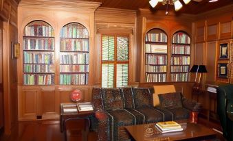 a living room with wooden furniture , including a couch and coffee table , surrounded by bookshelves filled with books at Harmony Hill Bed & Breakfast
