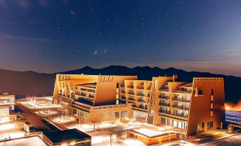 a night view of a modern building with many balconies and mountains in the background at Shahdag Hotel & Spa