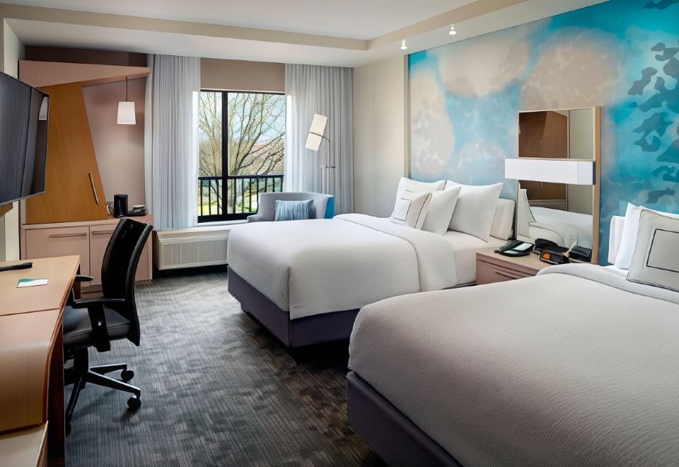 a modern hotel room with two beds , a window offering a view of the city , and a desk at Courtyard LaGrange