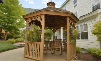 "a wooden gazebo with a rocking chair inside , surrounded by potted plants and a sign reading "" remembrance garden .""." at Courtyard Middlebury