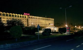 "a large hotel building with a red sign that says "" marriott "" and has a blue bus in front of it" at Islamabad Marriott Hotel