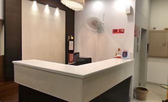 a white reception desk in a hotel lobby , with a chandelier hanging above it and various amenities on the desk at Hotel 8th Planet