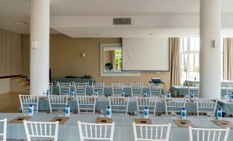 a conference room with rows of chairs arranged in a semicircle and a projector on the wall at Parador de Javea