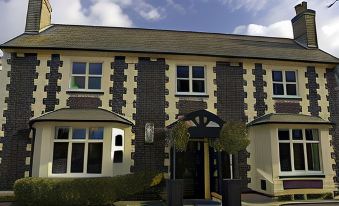 a black and white building with a red roof , situated in front of a blue sky at The Cadogan Arms