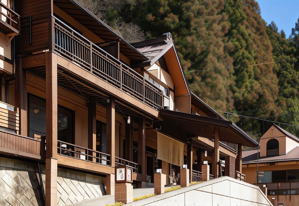 a row of brown wooden houses with balconies and a tree in the background , creating a picturesque scene at Shima Onsen Kashiwaya Ryokan