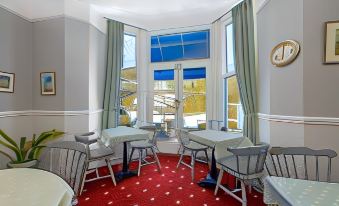a dining room with a table and chairs , red carpet , and large windows overlooking a scenic view at Bridgeside Guest House
