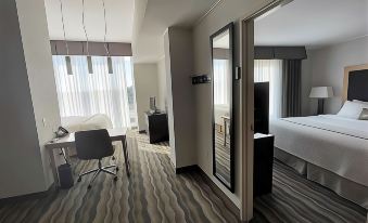 a hotel room with a bed , desk , and chair is shown with a view of the city through a window at Wyndham Avon