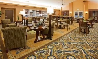 a spacious hotel lobby with various seating arrangements , including couches and chairs , as well as a dining area at Homewood Suites by Hilton Minneapolis-New Brighton