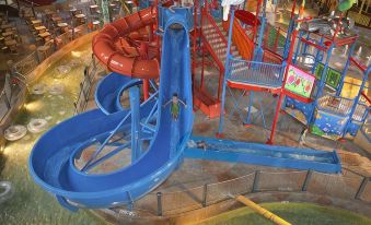 a man riding down a water slide at an indoor water park , surrounded by various water slides and play structures at DoubleTree by Hilton Hotel Boston North Shore