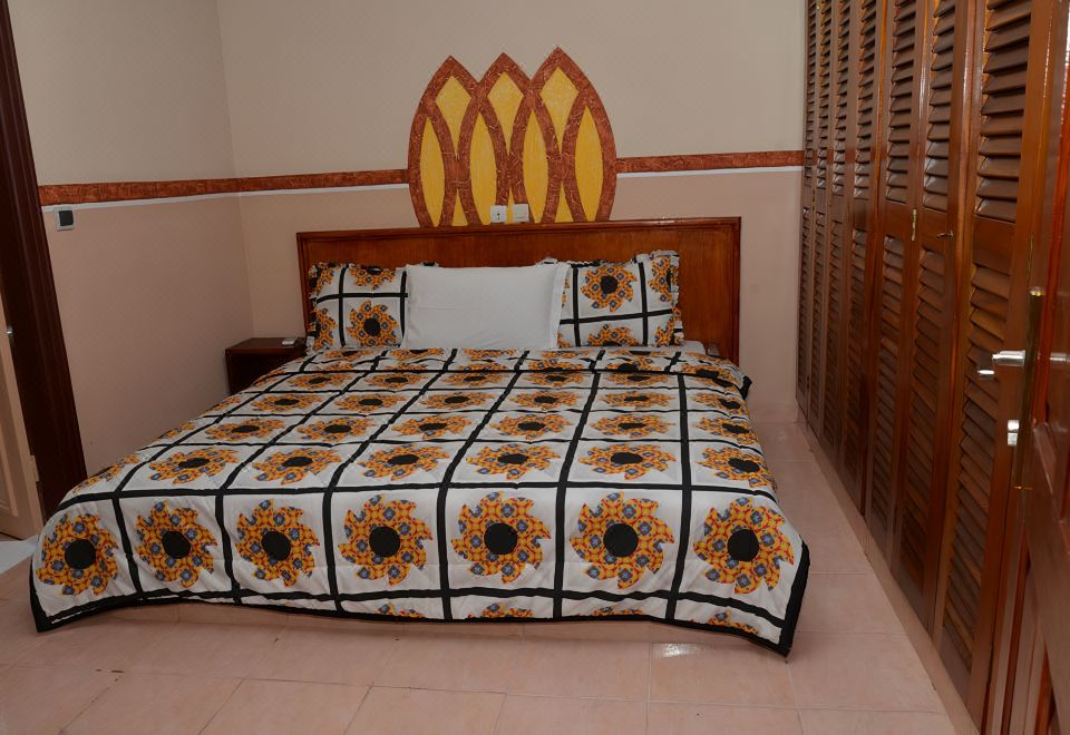 a bed with a black and white patterned comforter is situated in a room with wooden cabinets at Hotel International