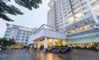 a large hotel building with a balcony and several cars parked outside , set against the backdrop of a rainy day at Kantary Hotel Kabinburi