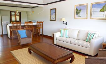 a cozy living room with a white couch , a wooden coffee table , and a dining area in the background at Santosha Barbados