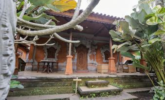 a traditional indonesian house with orange walls and wooden beams , surrounded by lush greenery and trees at Ubud Hotel & Cottages