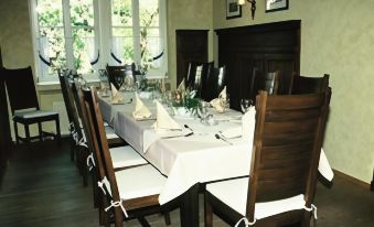 a dining room with a long table set for a formal dinner , complete with wine glasses , silverware , and napkins at Schlosshotel