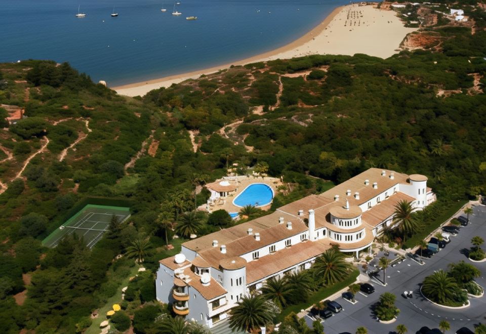 aerial view of a large building surrounded by trees , with a beach in the background at Hotel Casabela