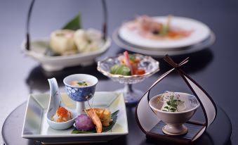 A table is adorned with plates and dishes filled with various foods, including dumplings at Fuji Ginkei