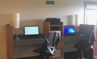 a desk with two laptops , a chair , and speakers is set up in a room at Lighthouse Suites Inn
