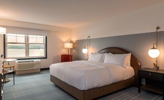 a large bed with white linens and a brown headboard is in a hotel room at Hotel Canandaigua, Tapestry Collection by Hilton