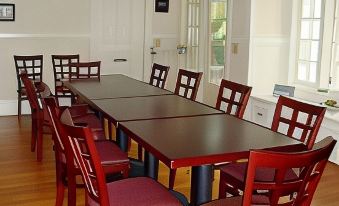 a large dining room with a long wooden table surrounded by chairs , all of which have red seats at Finger Lakes Bed and Breakfast